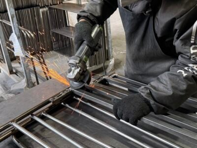 Metal frame furniture manufacturing including grinding to improve weld appearance and prepare surfaces for finishing